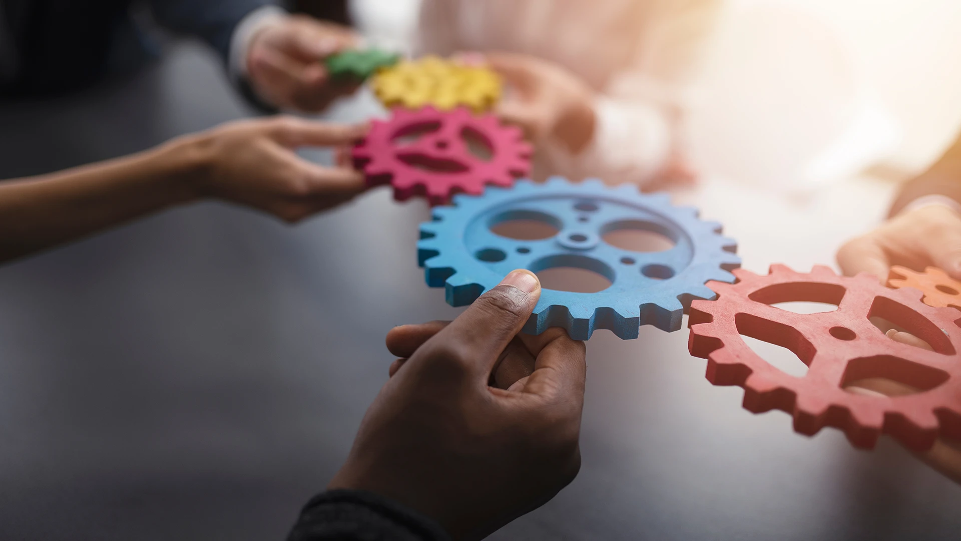 People holding cogs to form a gear assembly